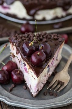 a piece of cake with chocolate and cherries on it is sitting on a plate