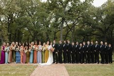 a large group of people in formal wear posing for a photo on a brick walkway