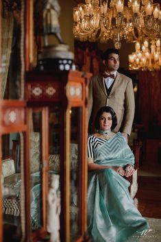 a man and woman standing next to each other in front of a chandelier