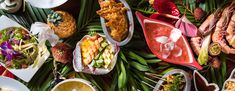 many different types of food are spread out on the table with green leafy leaves