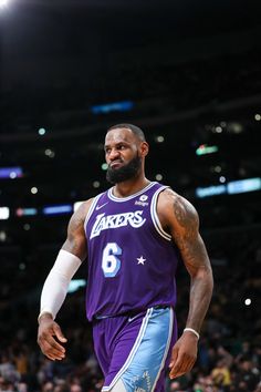 a man with a beard standing on top of a basketball court in front of a crowd