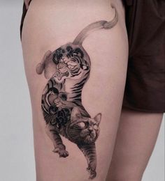 a woman's thigh with a cat tattoo on her leg and an image of a tiger