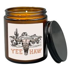 a jar filled with a candle that says yehw and an image of a cow skull on it