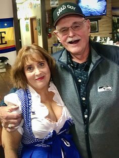 an older man and woman pose for a photo in front of a tv screen at a store