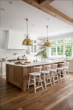 a large kitchen with wooden floors and white walls, along with an island in the middle