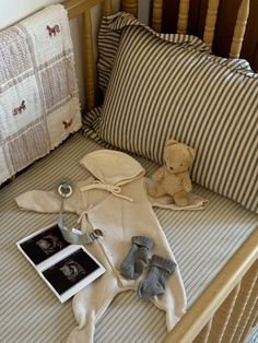 a teddy bear laying on top of a bed next to pillows and other stuff items