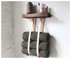 a wooden shelf with three rolls of toilet paper hanging from it's sides and two bottles on top