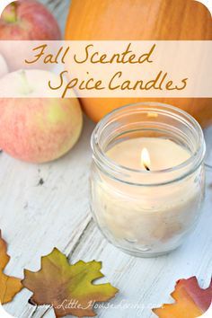 a candle that is sitting next to some apples and leaves on a table with the words, fall scented spice candles