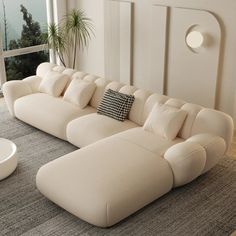 a large white couch sitting on top of a carpeted floor next to a window