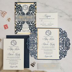 the wedding stationery is laid out on top of the table, including an ornate blue and gold laser cut pocketfold