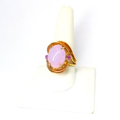 On offer is this beautiful Large Vintage 14k Yellow Gold Large Oval Translucent Lavender Jadeite Jade Ring with Two Sparkling Amethyst Gems on each side of this custom made ring.  This is a large ring with it's split shank rising above the finger with entwining gold bands around the large oval 6.7 Carat Translucent Lavender Jadeite Jade that is prong set and flanked by two sparkling round Amethyst gems.  The Lavender Jadeite measures 15mm long x 12 mm wide x 5 mm thick.  Each  round Amethyst mea Oval Amethyst Gemstone Ring, Elegant Pink Opal Ring For Formal Occasions, Formal Oval Kunzite Rings, Formal Pink Oval Opal Ring, Fine Jewelry Oval Kunzite Rings, Pink Oval Cabochon Opal Ring, Pink Oval Amethyst Ring, Split Shank Ring, Purple Jade