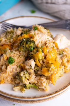 a white plate topped with rice and broccoli next to a silver fork on top of a table