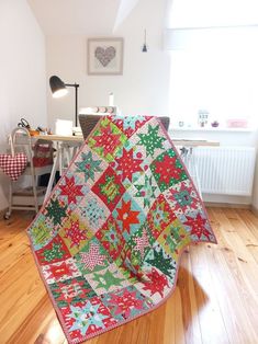 a quilted christmas tree sits on the floor in front of a desk and chair