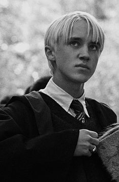 a boy with blonde hair wearing a sweater and tie