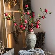 a vase filled with red flowers sitting on top of a table next to a window