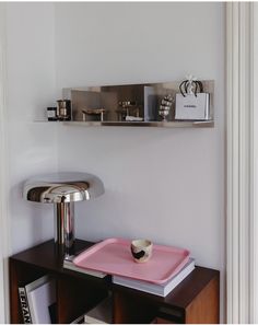 a table with a pink tray on top of it next to a wall mounted shelf