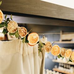 orange slices are hanging on a line with leaves