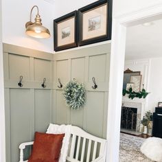 a white bench sitting in the corner of a room with two framed pictures above it