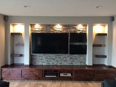 an entertainment center with built in shelves and television on the wall, along with two large flat screen tvs