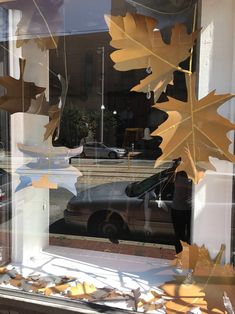 the window is decorated with autumn leaves and acorns in front of a car