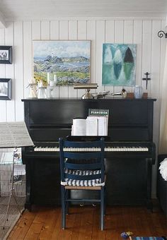 a living room with a piano in the corner and pictures on the wall above it