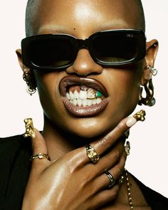 a woman wearing sunglasses and jewelry with her mouth open