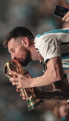 a man with tattoos on his arm kissing a soccer ball