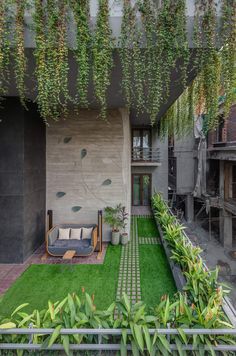 an outdoor living area with artificial grass and potted plants on the side of the building