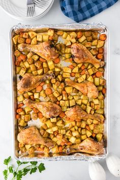 chicken, potatoes and carrots in a baking dish on a marble counter top with blue checkered napkin