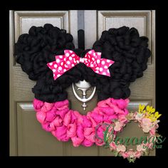 a minnie mouse wreath with pink and white polka dots on the top, hanging from a front door