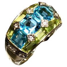 A beautifully made ring done in 18K yellow gold that has been set with 3.35cttw in blue topaz, 2.46cttw, 2.46cttw in green peridot and .09cttw in H-I color Si1-2 clarity diamonds… such a color combination! All weights are stamped inside of the shank. Dimensions/Weight: Ring measures .45” top to bottom and weighs 10.8g. Size 6 (sizable). Condition: All stones are secure and in perfectly wearable condition. R-TYE Luxury Fusion Multi-stone Rings, Luxury Multicolor Round Topaz Ring, Multi Gemstone Ring Jtv, Green Peridot, Color Ring, Dear Santa, Gem Stone, Cluster Ring, Color Combination