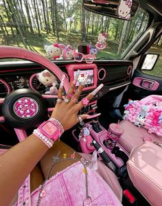 a person sitting in a car with hello kitty decorations on the dash board and steering wheel