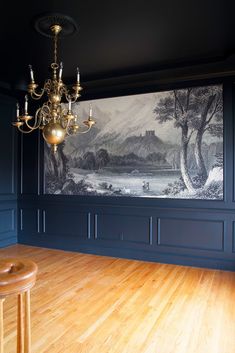 an empty room with a chandelier and painting on the wall behind it,