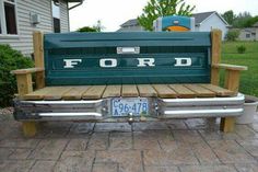 a green ford truck bench sitting on top of a wooden deck in front of a house