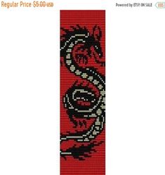 a red and black cross stitch bookmark with a dragon on it's side