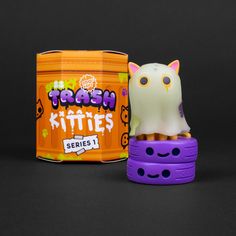 an orange and purple container with a white cat on it next to a purple toy