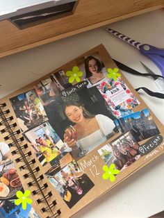 an open spiral notebook with photos and scissors next to it on a counter top,