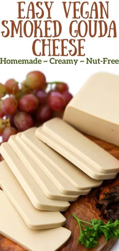 homemade vegan smoked gourmet cheese on a cutting board with grapes in the background