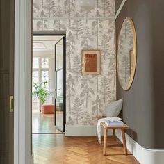 a hallway with wallpaper and wooden flooring in the middle, along with a mirror on the wall