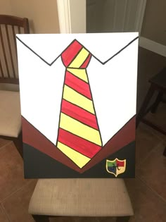 a painting of a tie on top of a white board with a brown chair in the background