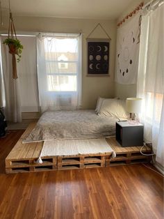 a bed made out of wooden pallets in a room with hardwood floors and windows