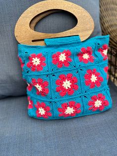 a crocheted purse with a wooden handle sitting on a couch next to pillows