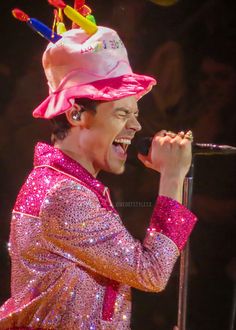 a man in a pink hat singing into a microphone