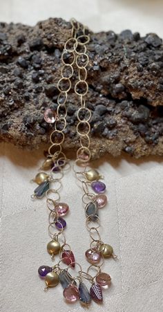 This necklace is made from gold chain with charms of amethyst briolettes, mystic topaz free form gems, light pink sapphire briolettes, and carved tourmaline leaves dangling freely with gold accent beads. Good luck and good fortune are some of the benefits believed to be bestowed upon the wearer of mystic topaz.    	Gemstones: Amethyst, Mystic Topaz, Pink Sapphire and Tourmaline  	14K Gold Filled Chain, Lobster Claw Clasp and Gold Accent Beads  	Length: 18 Inches Chain With Charms, Hope Necklace, Mystic Topaz, Gold Accent, Good Fortune, Gold Filled Chain, Pink Sapphire, Necklace Designs, Gold Accents