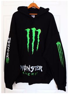 a black monster energy hoodie hanging on a door