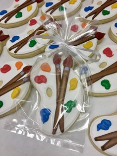 decorated cookies in the shape of paintbrushes and palettes are on a table