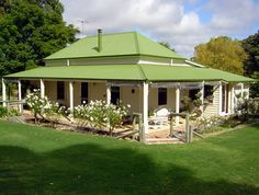 a green roofed house with white flowers in the front yard