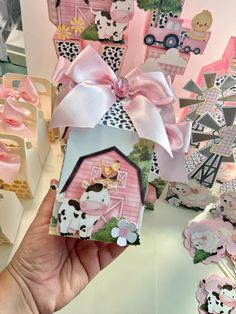 a hand holding up a small pink and white box with farm animals on it's side