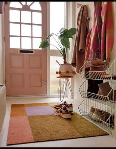 a pair of shoes is on the floor in front of a pink door and some coat racks