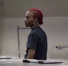 a man with red dreadlocks standing in front of a mirror